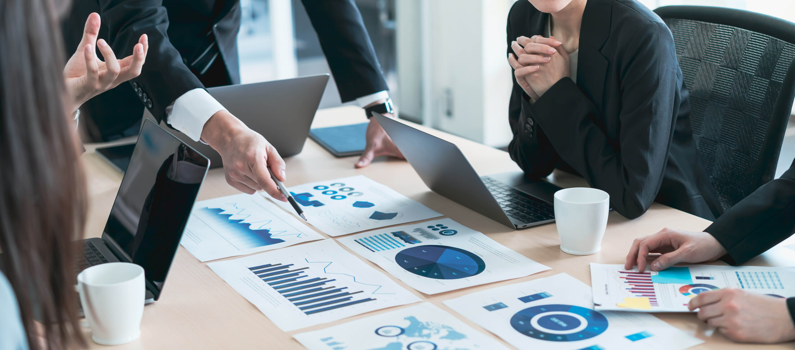 Two people are sitting at a table with laptops.